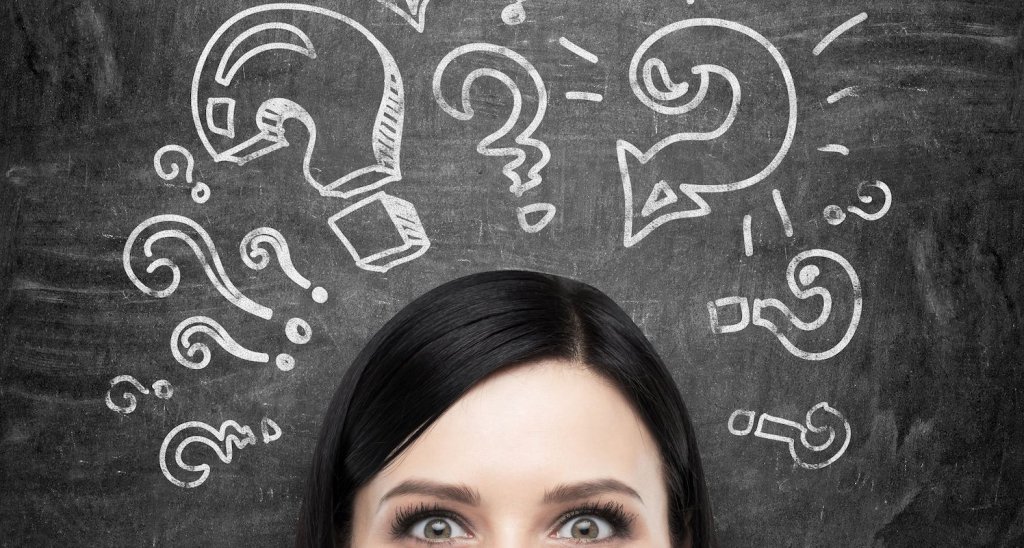44482710 - a forehead of the brunette girl who is pondering about unsolved problems. question marks are drawn around the head. black chalkboard background.