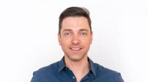 Rodrigo Rodrigues, CTO global da Serasa Experian, em um retrato profissional. Ele está sorrindo levemente, veste uma camisa social azul e tem cabelos curtos e castanhos. O fundo branco destaca sua imagem, conferindo um tom clean e corporativo à fotografia.