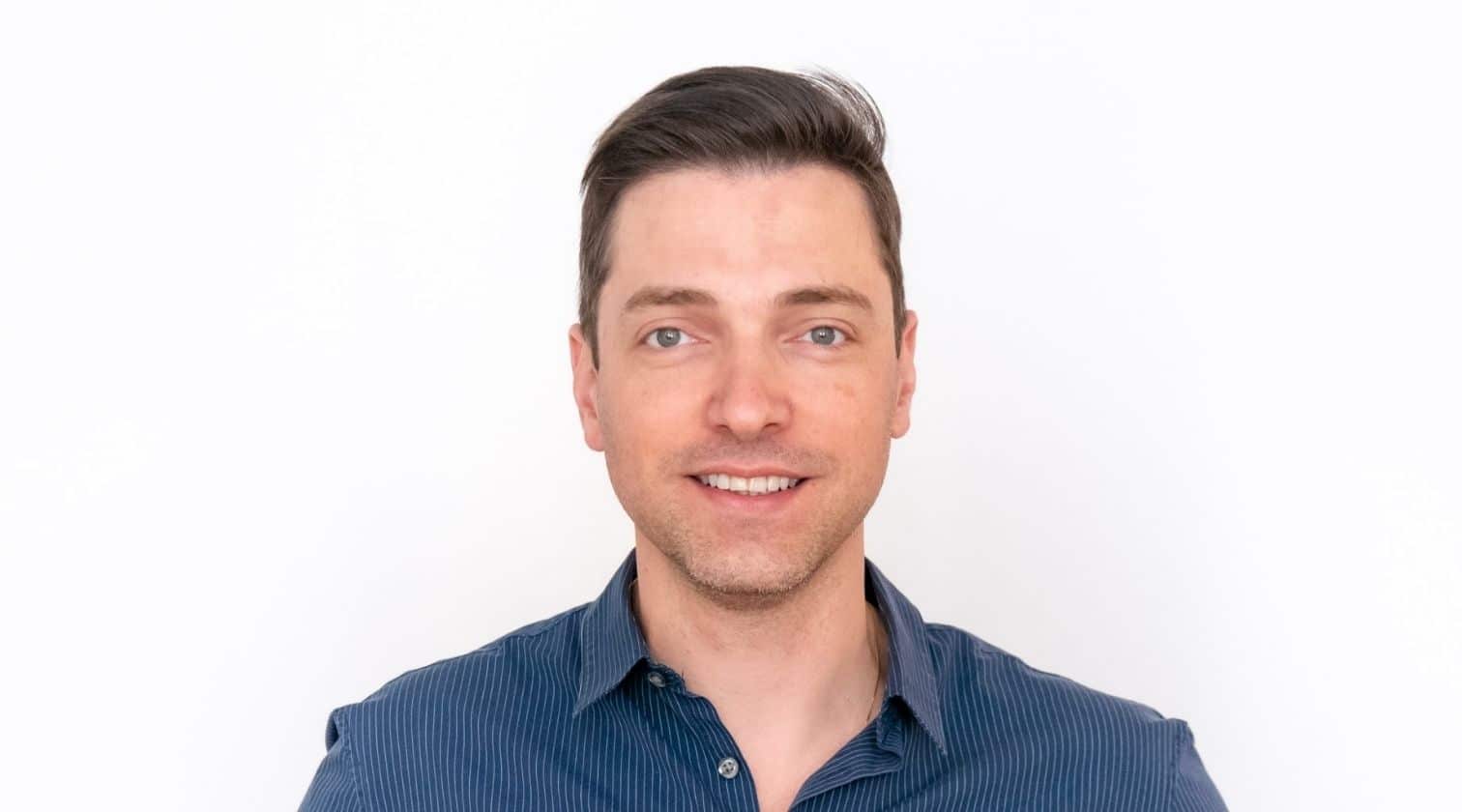 Rodrigo Rodrigues, CTO global da Serasa Experian, em um retrato profissional. Ele está sorrindo levemente, veste uma camisa social azul e tem cabelos curtos e castanhos. O fundo branco destaca sua imagem, conferindo um tom clean e corporativo à fotografia.