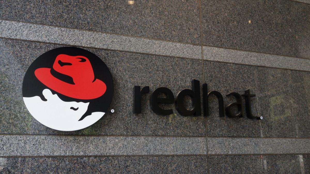 Logotipo da Red Hat em uma parede de granito, com o ícone de um chapéu vermelho em um círculo preto ao lado da palavra 'redhat' em letras minúsculas pretas