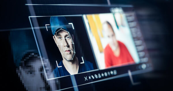 Tela de computador exibindo um sistema de reconhecimento facial analisando o rosto de um homem de boné, com um padrão geométrico sobreposto à sua face. Ao lado, uma imagem de outra pessoa, sugerindo um possível caso de deepfake ou identificação digital. A cena representa tecnologia de inteligência artificial e segurança digital (identificação, deepfake, fake news, inteligência artificial, ia, notícias falsas, riscos, cibersegurança, segurança, vídeos falsos, bytedance)