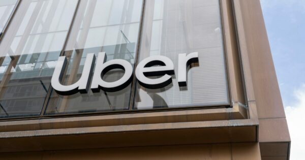 Prédio de vidro com bordas de madeira, placa escrito Uber em letreiros metálicos