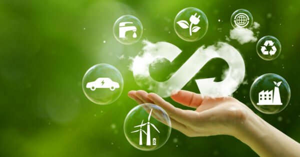 Ilustração representando economia circular, com uma mão sustentando ícones dentro de bolhas que simbolizam sustentabilidade, como energia renovável, reciclagem, mobilidade elétrica, preservação ambiental e gestão de recursos hídricos. Ao fundo, um cenário verde remete à natureza, reforçando a ideia de práticas sustentáveis e integração com o meio ambiente