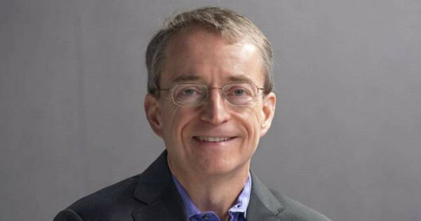 A imagem mostra Pat Gelsinger, CEO da Intel, posando com um sorriso e braços cruzados. Ele está usando um terno escuro com uma camisa azul claro por baixo. O fundo da imagem é simples e neutro, com uma parede cinza, criando um ambiente corporativo profissional. Pat Gelsinger tem uma expressão amigável e confiante, transmitindo liderança e acessibilidade (Patrick Gelsinger Intel)