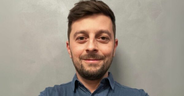 Retrato de Caio Galantini, diretor executivo e cofundador da HVAR. Ele está sorrindo levemente, tem barba curta e cabelo castanho penteado para o lado. Veste uma camisa azul e posa diante de um fundo neutro e levemente texturizado (Google Cloud)