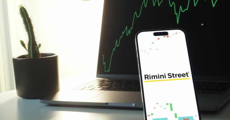 Telefone com os dizeres "Rimini Street" e um computador atrás