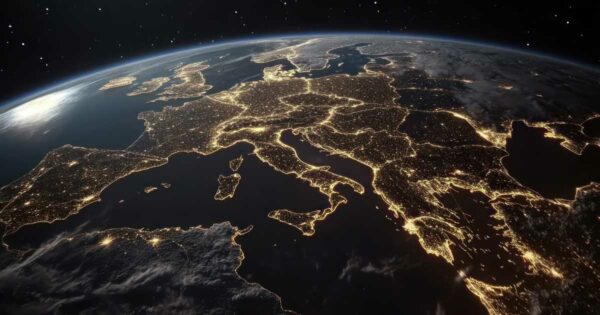 Imagem da Europa vista do espaço durante a noite, com as luzes das cidades iluminando o continente e destacando as principais regiões urbanas. A cena transmite a ideia de conectividade, tecnologia e desenvolvimento urbano, com destaque para países como Itália, França, Alemanha e Reino Unido.
