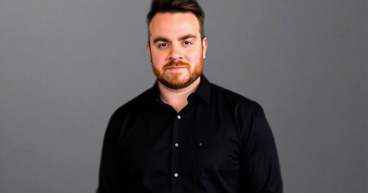 Pólen Kuhnen, country manager da CM Mobile, vestindo uma camisa preta de botões está posicionada diante de um fundo cinza liso. Não há outros elementos visuais ou texto na imagem.
