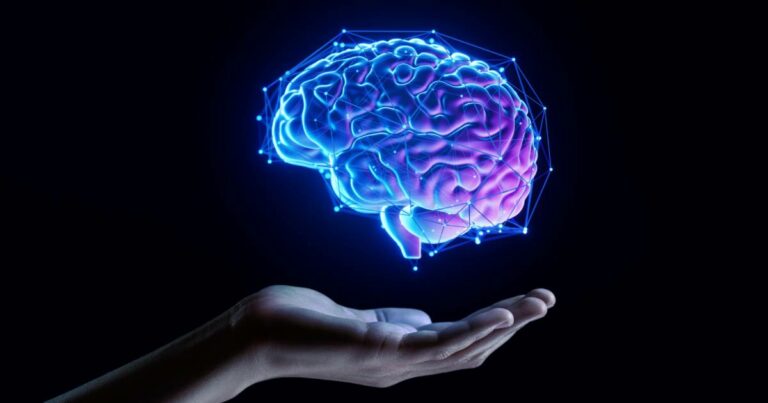 Mão estendida com a palma voltada para cima sustentando uma representação holográfica de um cérebro em tons de azul e roxo, envolto por uma rede de conexões digitais. A imagem remete à inteligência artificial, tecnologia e inovação no campo da mente e dados (zero trust, valor, neural, cientista, interface, organização, experience, mestres, economico, identidades)