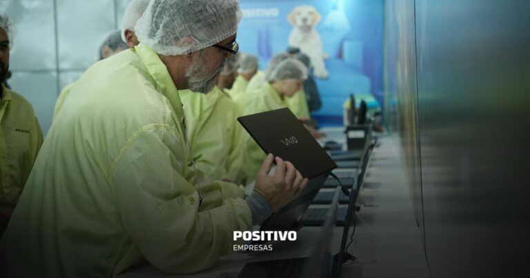 Funcionários na fábrica da Positivo Tecnologia testando produtos eletrônicos em uma linha de produção moderna, buscando reduzir o débito tecnológico par ao negócio.