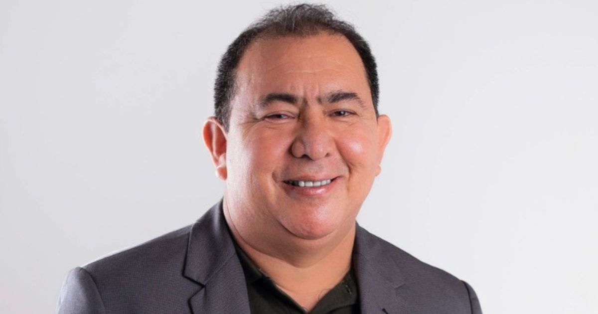 A imagem mostra uma pessoa vestindo um blazer escuro sobre uma camisa polo preta. O fundo é simples e de cor clara, provavelmente branco ou cinza claro, com iluminação uniforme, sugerindo um ambiente de estúdio ou foto profissional. A composição transmite uma aparência formal ou corporativa, típica de retratos usados para perfis profissionais ou institucionais. (startups)